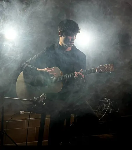 Musniac tocando la guitarra entre humo y focos