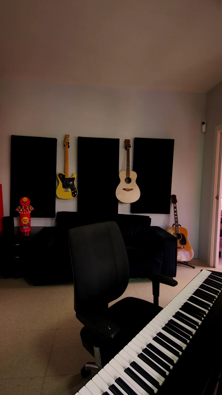 La sala con guitarras colgadas, sofá y piano